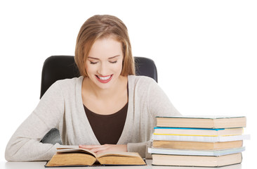Beautiful student woman sitting by the desk with books and learn