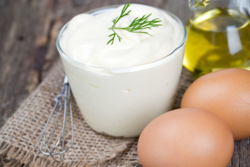 Obraz na płótnie Canvas Mayonnaise in bowl with egg and olive oil on an old wooden table