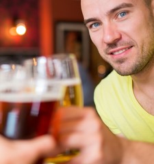 Handsome young man toasting with beer in a pub