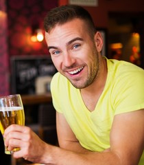 Handsome young man with light beer in a pub