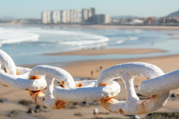 Naklejka premium Metal chain fence over city beach background