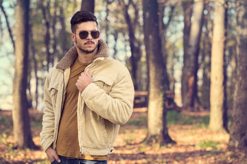 Stylish man posing in autumn park