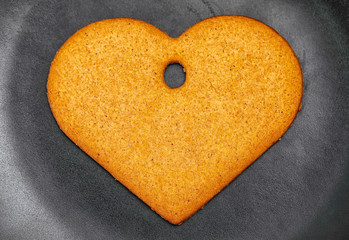 Heart shaped gingerbread cookie on the black plate