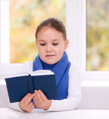 Little girl is reading a book