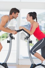 Fototapeta na wymiar Determined couple working out at spinning class