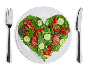 Heart shape of various vegetables and herbs on white plate