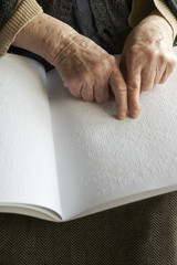 Old woman' s hands, reading a book with braille language