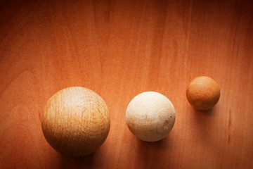 Three wooden balls on a wooden board.