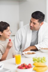 Smiling young son with father having breakfast