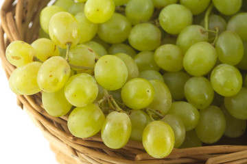 Lot of ripe grape bunches in brown wicker basket closeup