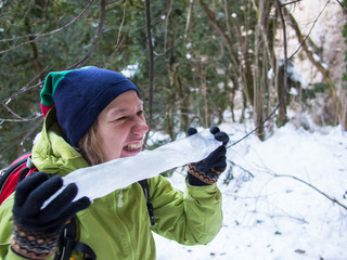 Woman eating a big icicle on a background of trees