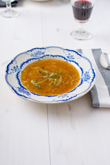 Classic french onion soup on a white wood table with some red wi