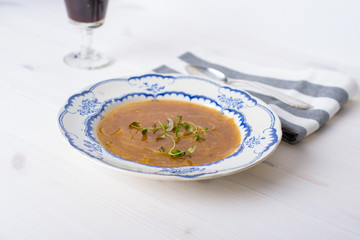Classic french onion soup on a white wood table with some red wi