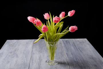 Tulips on a blue gray wood table with black background