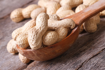 peanuts in shell closeup in brown wooden spoon