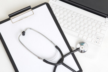 laptop keyboard, stethoscope and clipboard with blank paper shee
