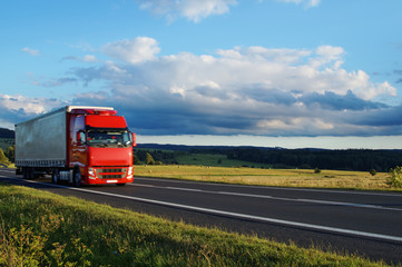 Rural landscape with road and moving red truck