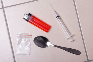 drug syringe, heroin powder in package, spoon and lighter on the