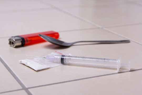 drug syringe, heroin powder, spoon and lighter on the floor