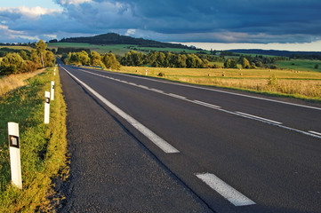 Asphalt road through the fields towards the horizon