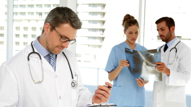 Doctor looking at clipboard then smiling at camera