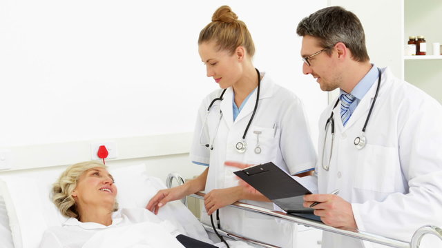 Doctors speaking with sick patient in bed