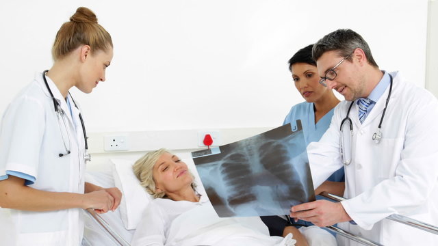 Doctors explaining xray to patient in bed