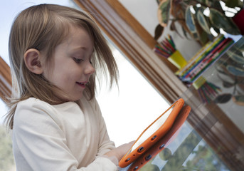 child in a home interior engrossed in a game on a digital tablet