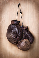 old boxing gloves hang on nail on wall