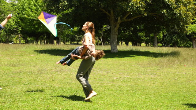 Little boy and parents flying a kite and messing in the park