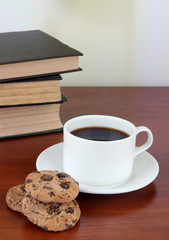 Cup of coffee with cookies and books