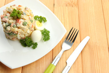 Russian traditional salad Olivier, on wooden background