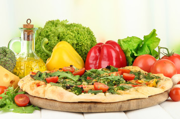 Tasty vegetarian pizza and vegetables on wooden table