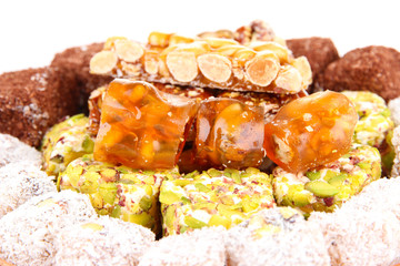 Tasty oriental sweets on wicker tray, isolated on white