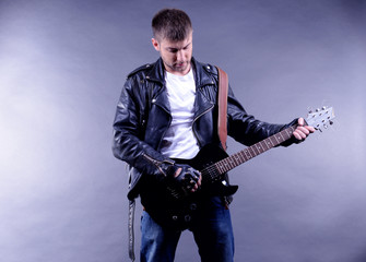 Young musician playing  guitar on gray background