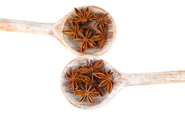 Star anise in wooden spoons, isolated on white