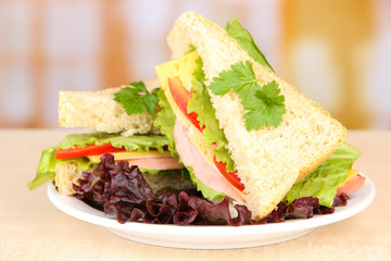 Fresh and tasty sandwiches on plate on table on light