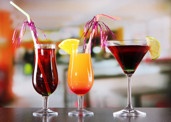 Glasses of tasty cocktails on bright background