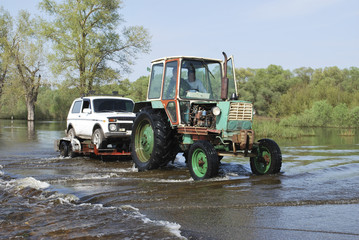 Floods, it flooded road tractor carries cars.