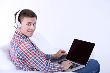 Guy sitting on sofa and  listening to music on white background