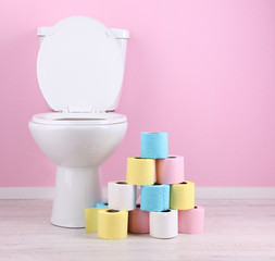 White toilet bowl and colorful rolls of toilet paper, in