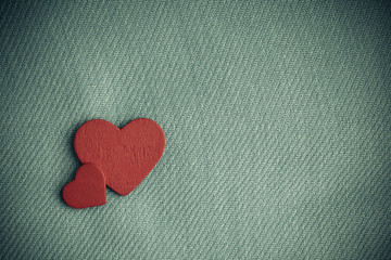 Red wooden decorative hearts on gray cloth background.