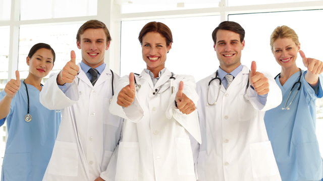 Confident medical team looking at camera and giving thumbs up