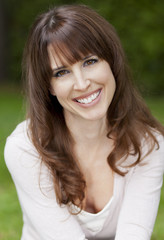 Fototapeta premium Pretty woman smiling at the camera in front of her house