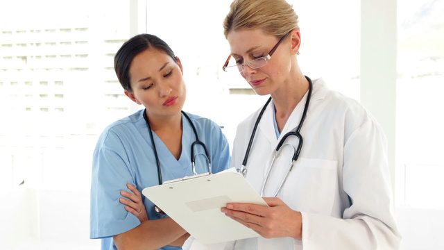 Two medical workers looking over a file and looking at camera