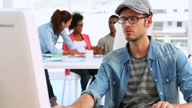 Designer working with colleagues talking behind him