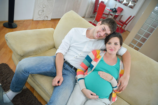 pregnant couple at home using tablet computer