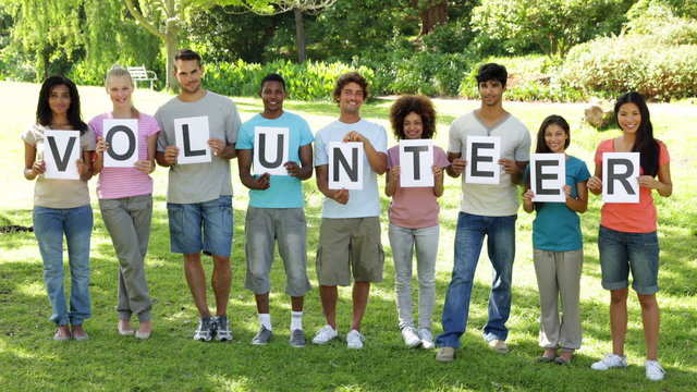 Group of casual young friends smiling at camera holding letters