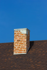 The brick chimney in bright sunlight a deep blue sky vertical