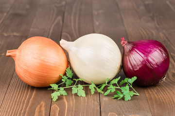Yellow, withe and red onion on a wooden background